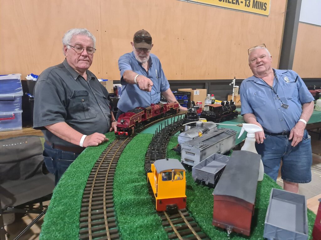 3 men of the garden group of AMRA standing with some model trains